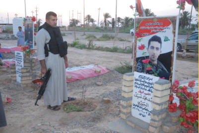 Ettaba (L) stands at the gravesite of a good friend killed in battle whose name was Yousef.